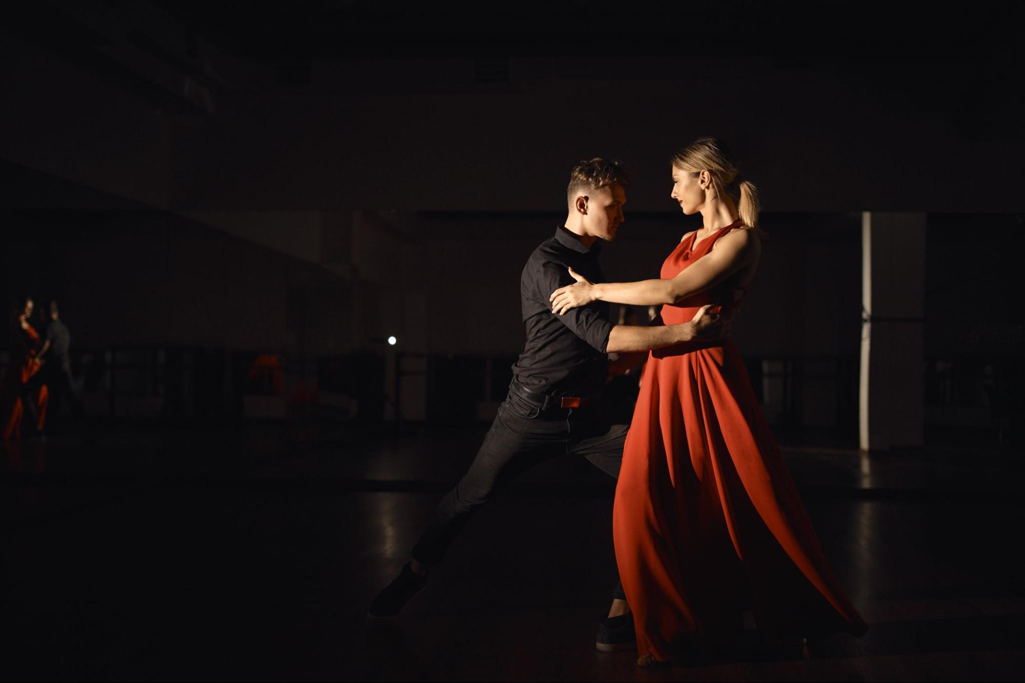 Couple performing an elegant Bachata dance routine under stage lighting