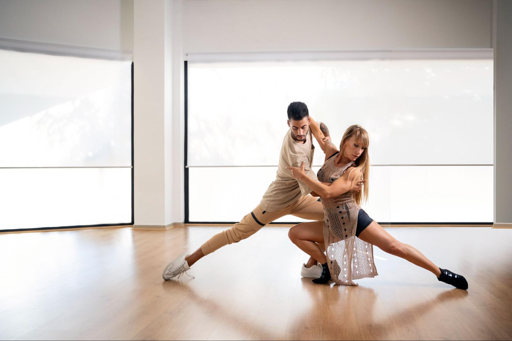 Dance partners rehearsing Bachata footwork and partner connection in a bright studio